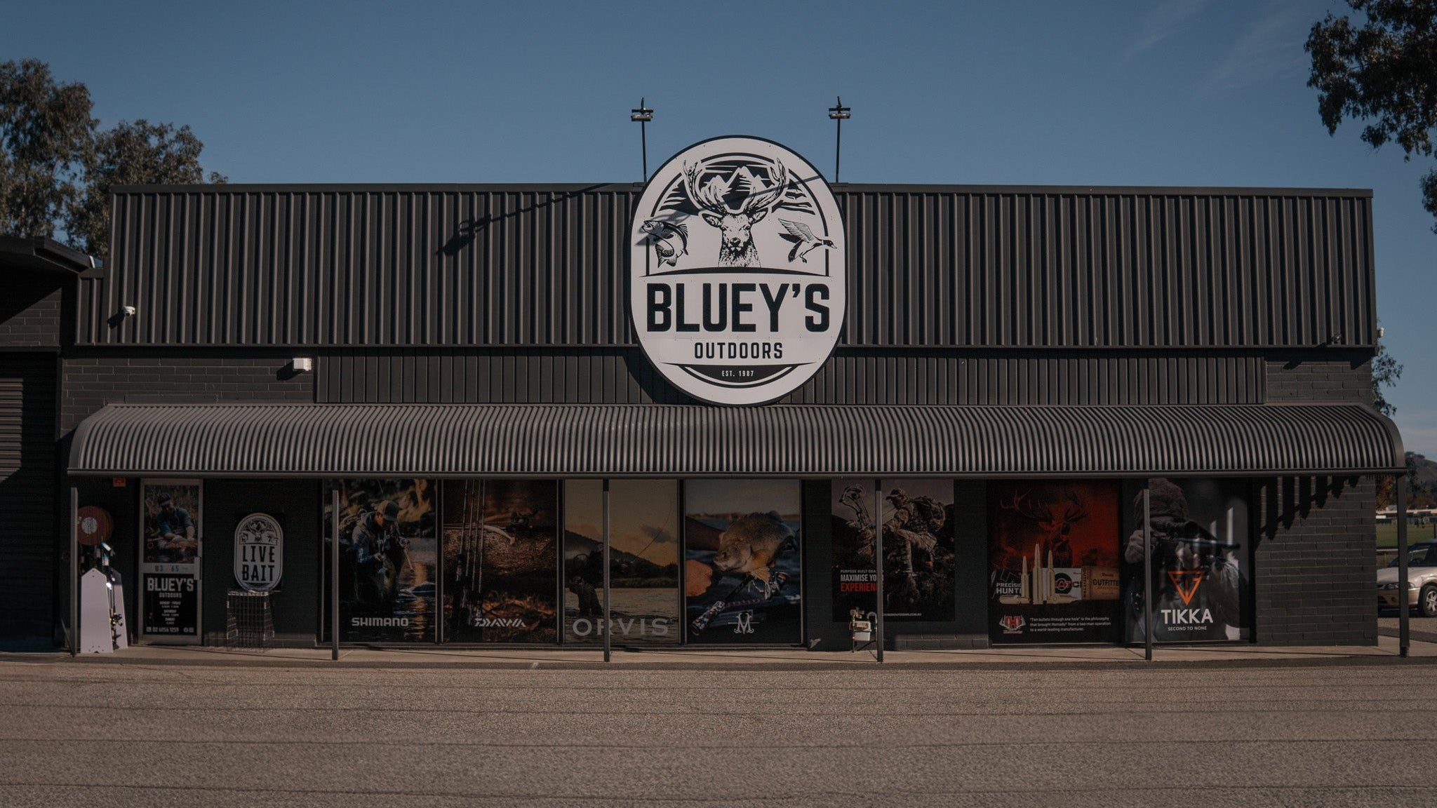 Storefront with 'Bluey's Outdoors' sign on a clear day